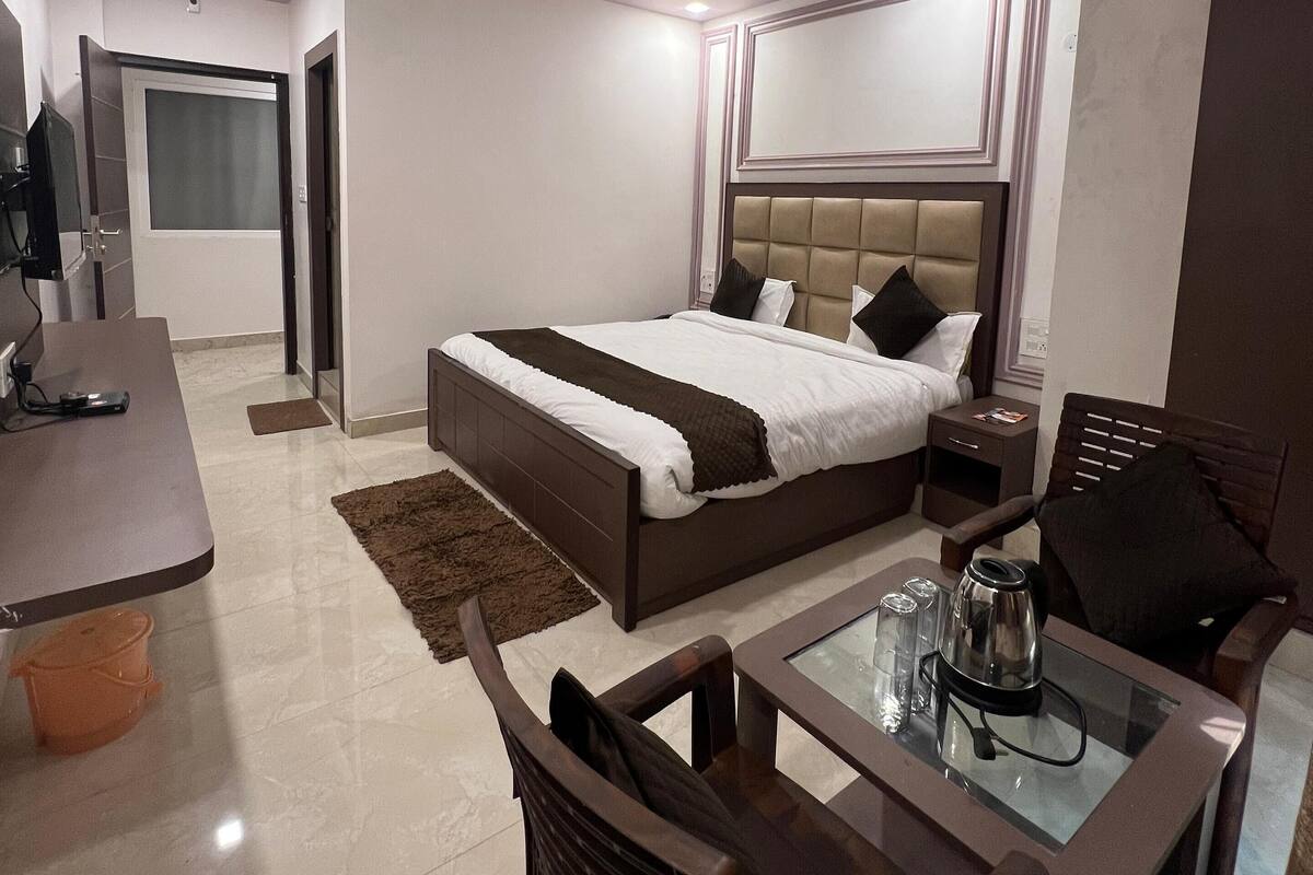 A modern hotel room with a large bed, a desk, and a chair.