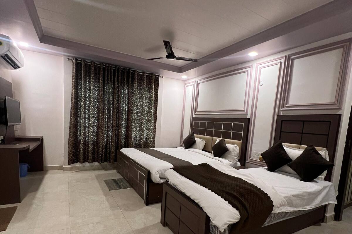 A bedroom with two beds, a desk, and a ceiling fan.