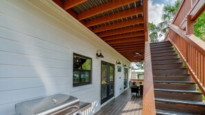 A covered deck with a barbecue grill, wooden stairs, and a view of the outdoors. - Forget your worries in this serene space. New 4-bedroom 4 bath house in Astor (Astor)