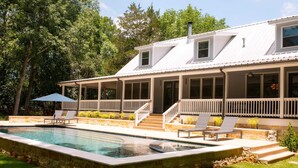 Une maison avec une piscine, un patio couvert et un escalier menant à l’entrée principale.