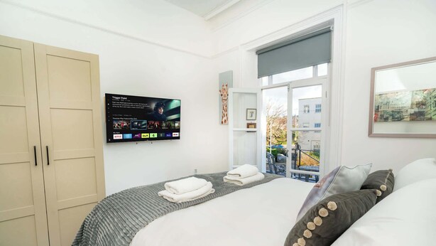 Ein Hotelzimmer mit Bett, Wandfernseher, Kleiderschrank und Fenster mit Ausblick.