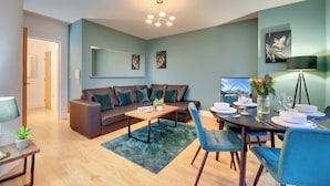 En moderne stue med sofa, sofabord og spisebord dækket til et måltid.