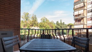 A balcony with a table and chairs, overlooking a garden and buildings. - JOIVY Flat with access to central Rome (Rome)