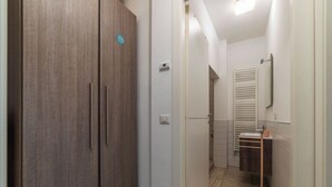 A narrow hallway with a wooden wardrobe, a light switch, and a towel rack. - JOIVY Flat with access to central Rome (Rome)