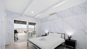 Ein modernes Schlafzimmer mit einem großen Bett, einem Nachttisch und Blick auf einen Balkon.