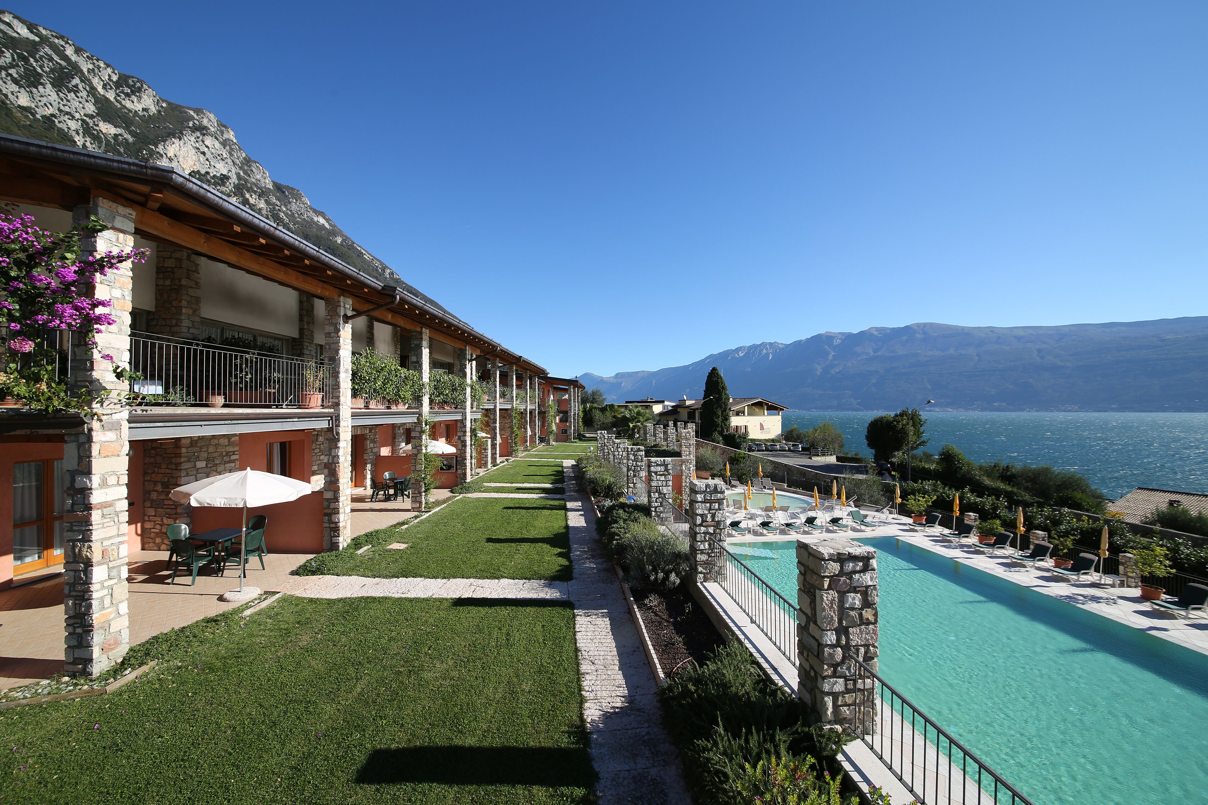 Un hotel con piscina, mobiliario de exterior y vistas a las montañas.