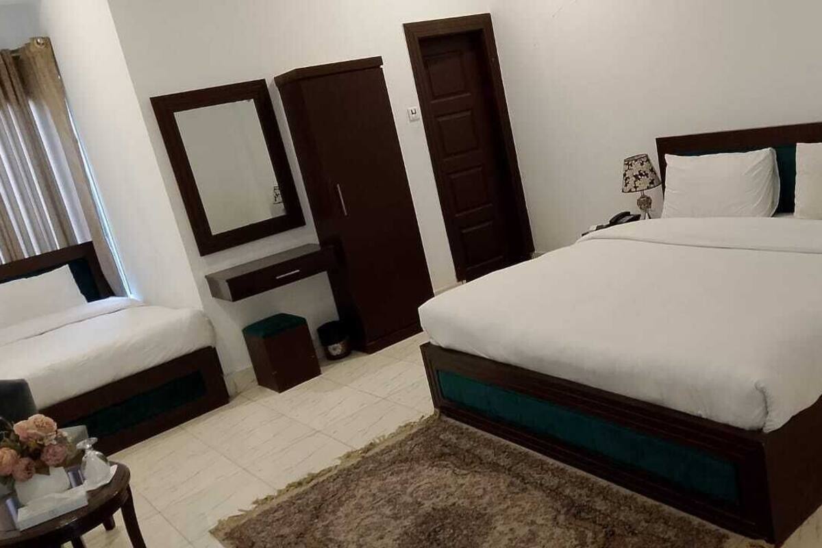 A bedroom with a large bed, a dresser, a mirror, and a door.