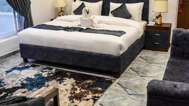 A hotel room with a large bed, two bedside tables, a chair, and a view of the outdoors.