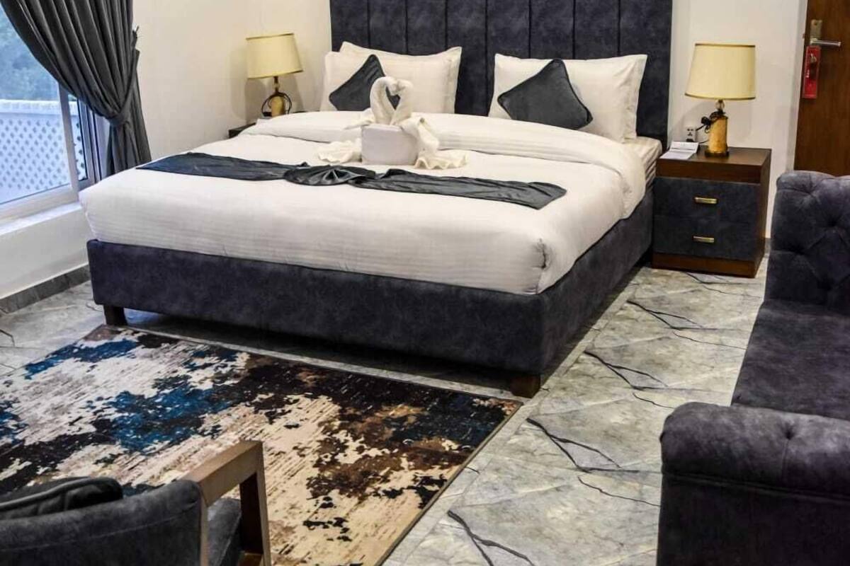 A hotel room with a large bed, two bedside tables, a chair, and a view of the outdoors.