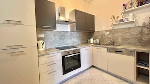 Eine moderne Küche mit grauen Schränken, einem eingebauten Backofen und einem Spülbecken.