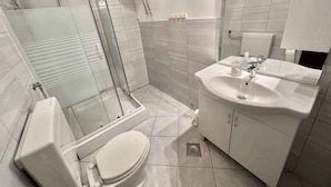 Ein modernes Badezimmer mit Duschkabine aus Glas, einer weißen Toilette und einem Waschbecken mit Spiegel darüber.