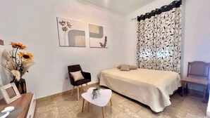 Ein Schlafzimmer mit einem Bett, einem Sessel, einem kleinen Tisch und Bildern an den Wänden.