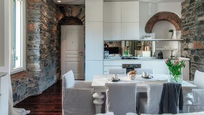 A dining area with a stone wall, white cabinets, and a brick archway. - Stunning Central Como apt by JOIVY  (Como)