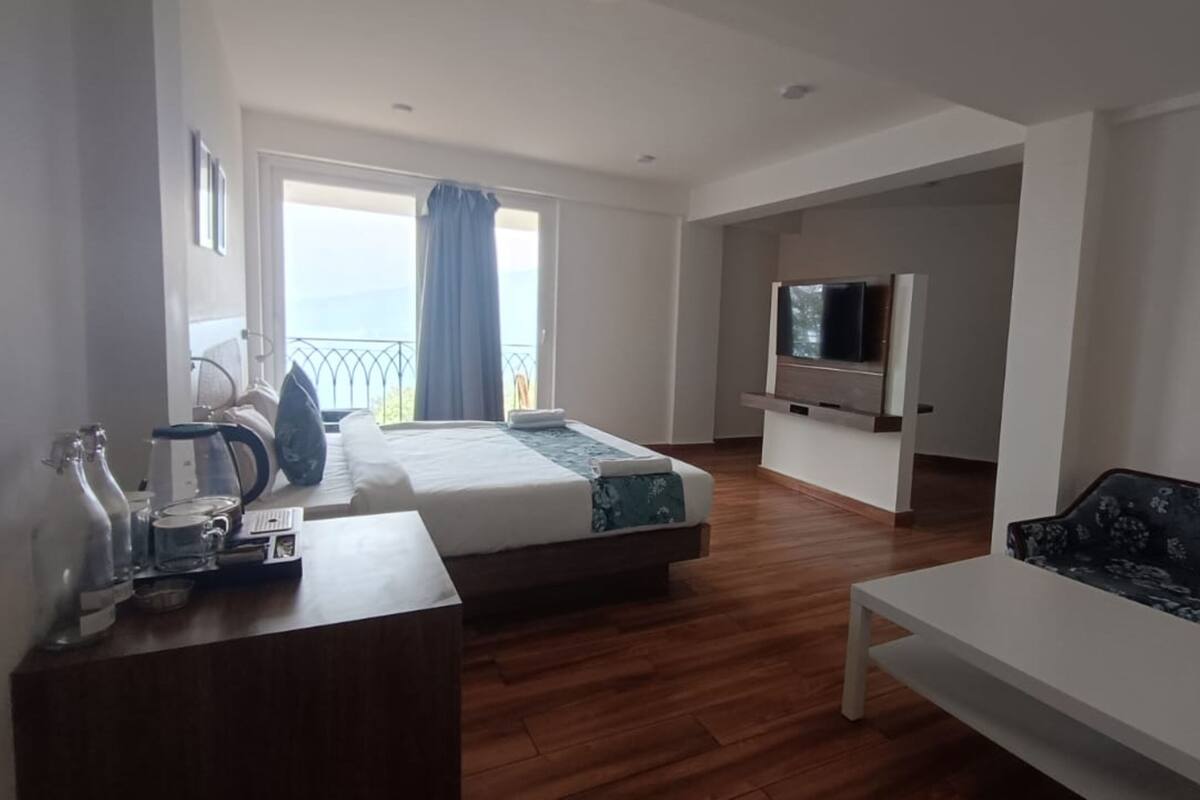 Een hotelkamer met een bed, een bank, een televisie en een balkon met uitzicht.