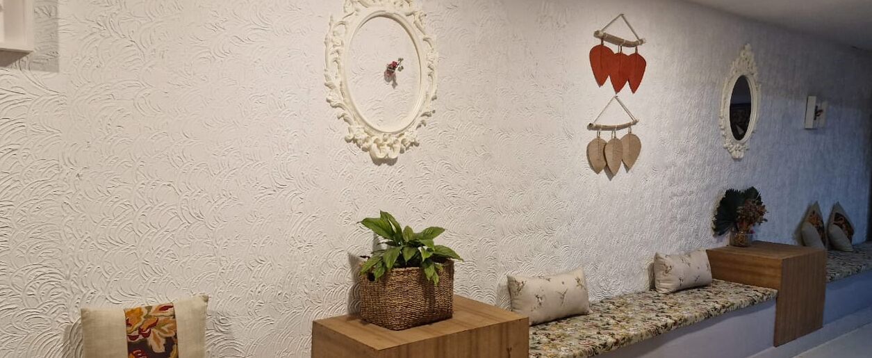A hallway with a textured wall, a wicker basket with a plant, and a sofa with cushions.