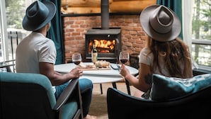 A couple seated at a table with a wood-burning stove in the background.