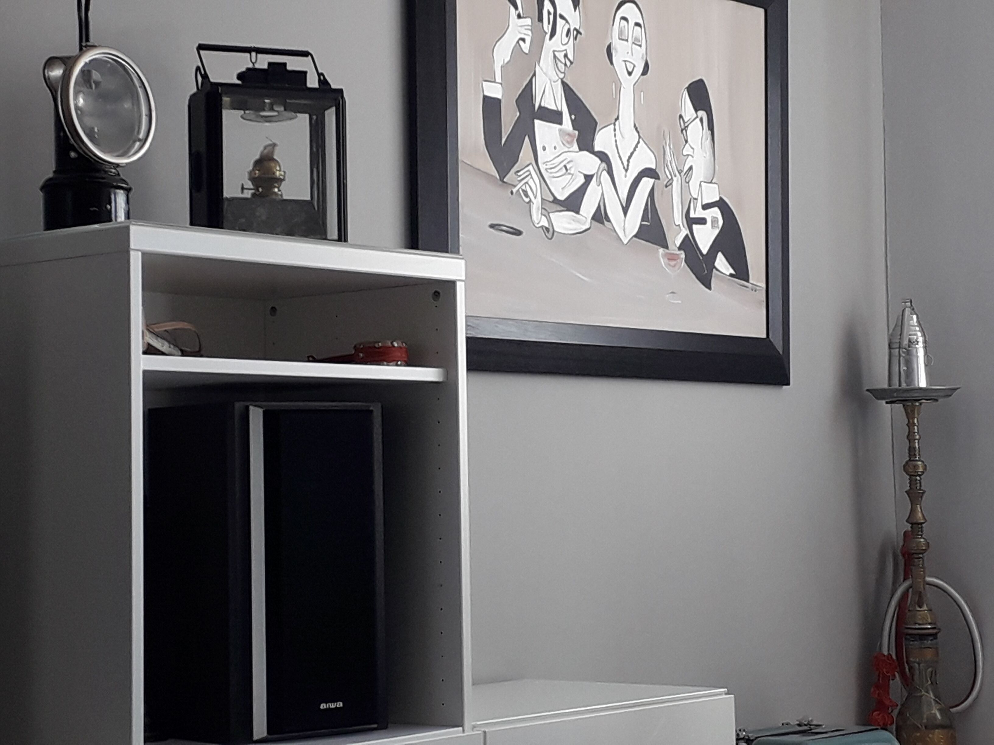 A room with a white cabinet, a framed artwork, and a hookah on the right side.
