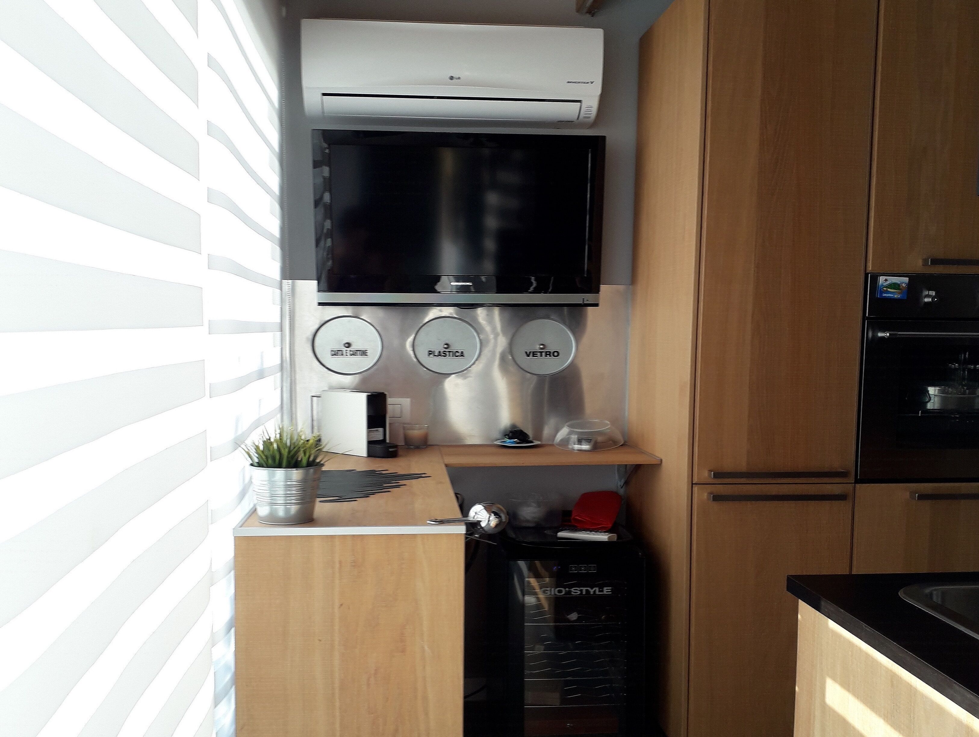 Een kleine keuken met een ingebouwde televisie, een koffieapparaat en een koelkast.