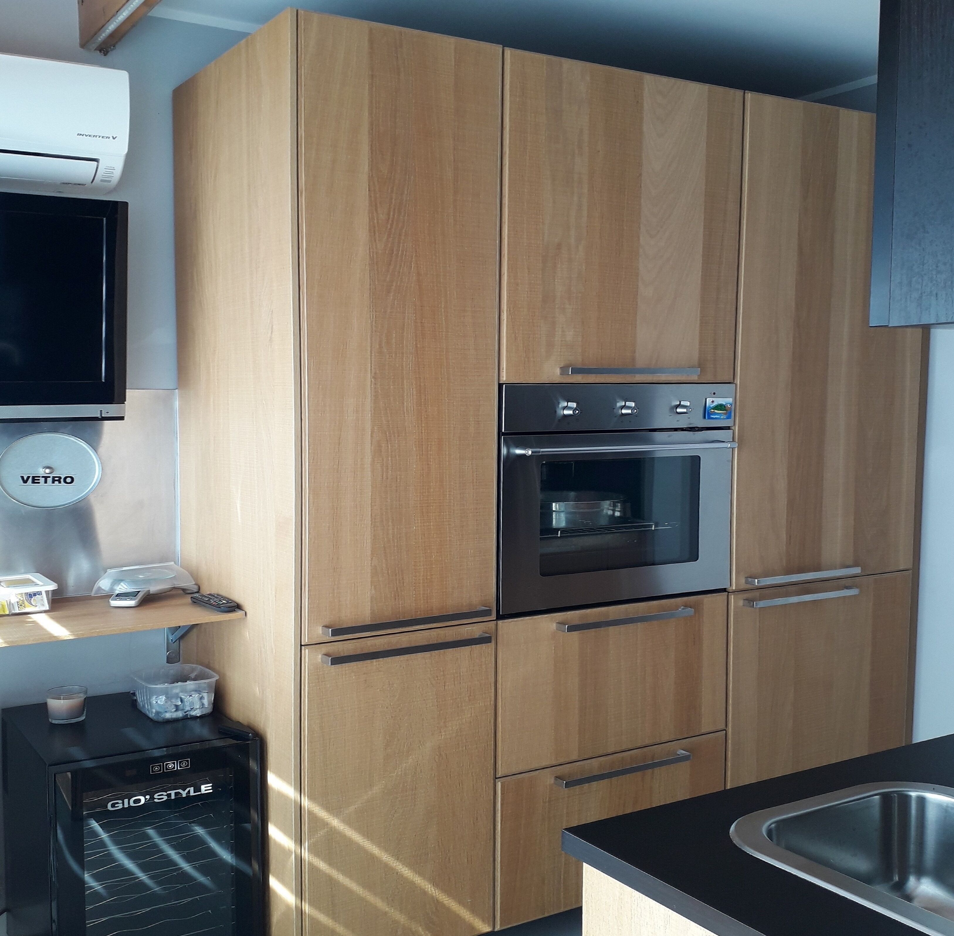 Eine moderne Küche mit Holzausstattung, einem Backofen, einem Kühlschrank und einer Spüle.