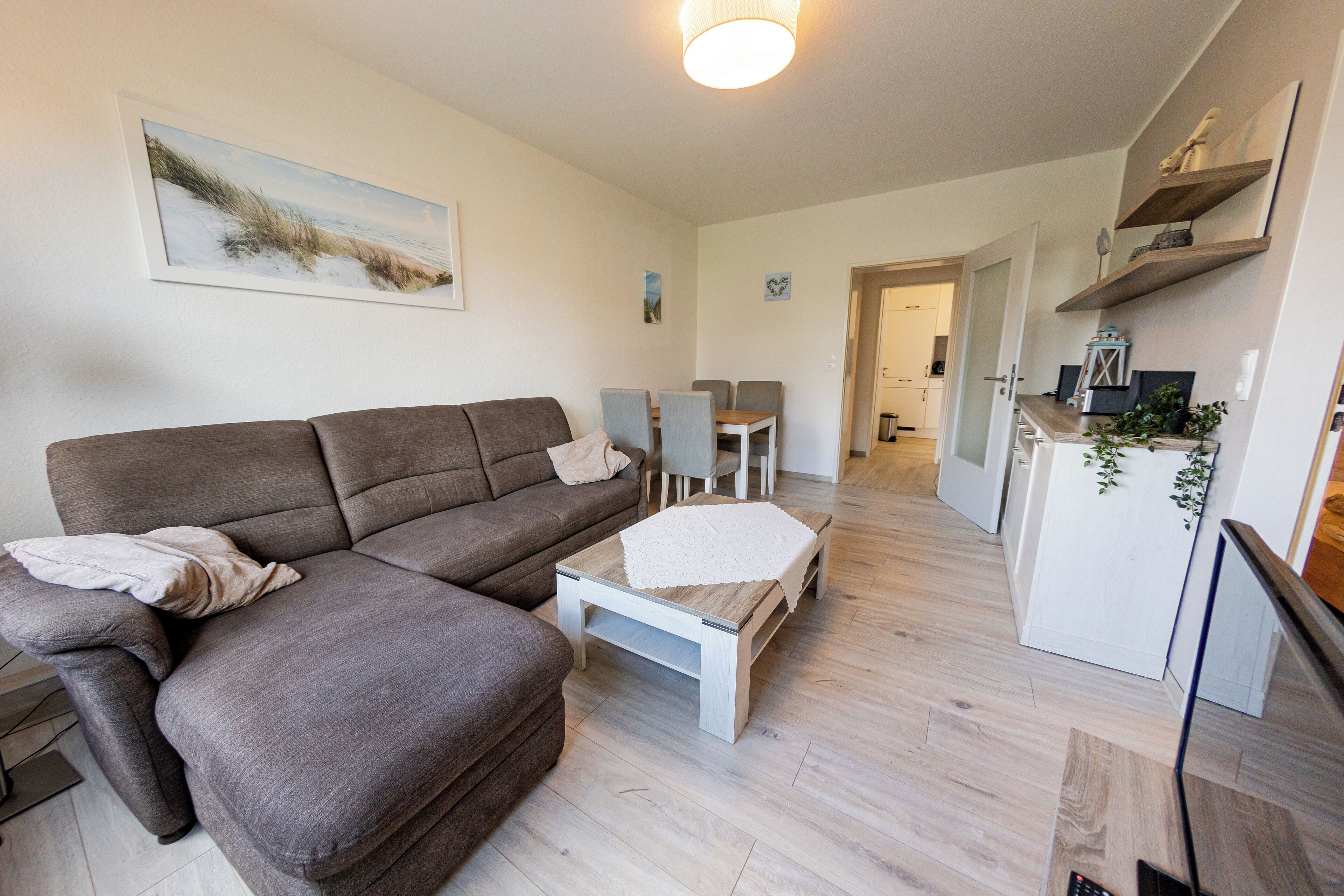 En moderne stue med en modulsofa, et lille sofabord og et spiseområde med bord og stole.