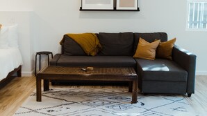 A modern living room with a sofa, coffee table, and a patterned rug. - Adorable Studio - Private Patio - Dream Kitchen (Waco)
