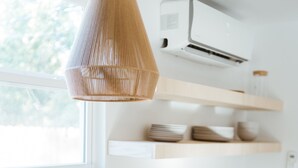 A modern kitchen with a black sink, white cabinets, a wooden countertop, a hanging light fixture, and a built-in air conditioner. - Adorable Studio - Private Patio - Dream Kitchen (Waco)