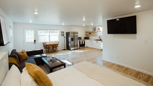 A modern living room with a sofa, coffee table, and a dining area with a table and chairs. - Adorable Studio - Private Patio - Dream Kitchen (Waco)