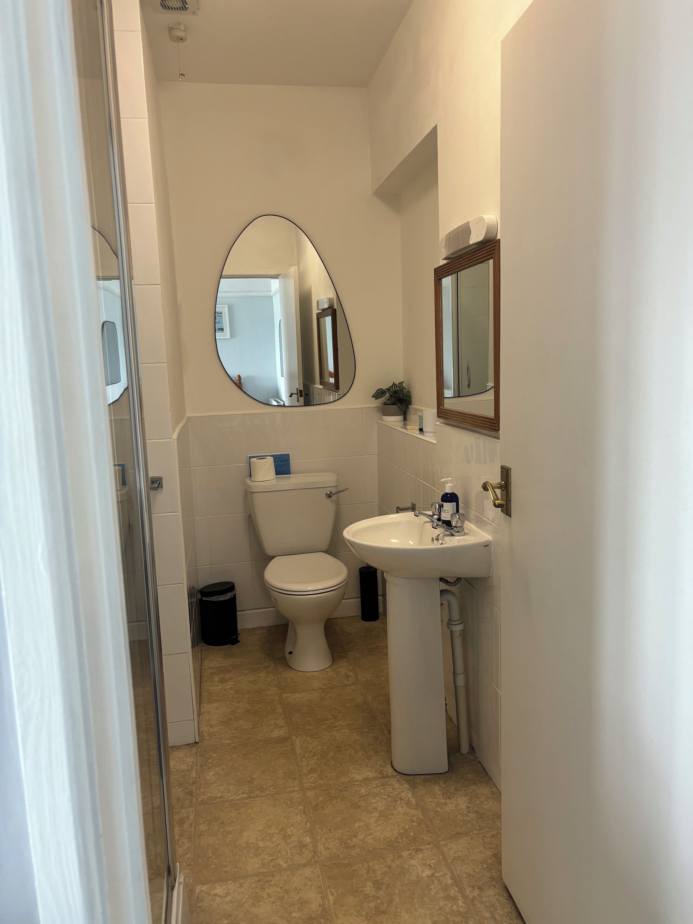 Un baño pequeño y limpio con inodoro, lavamanos y espejo.