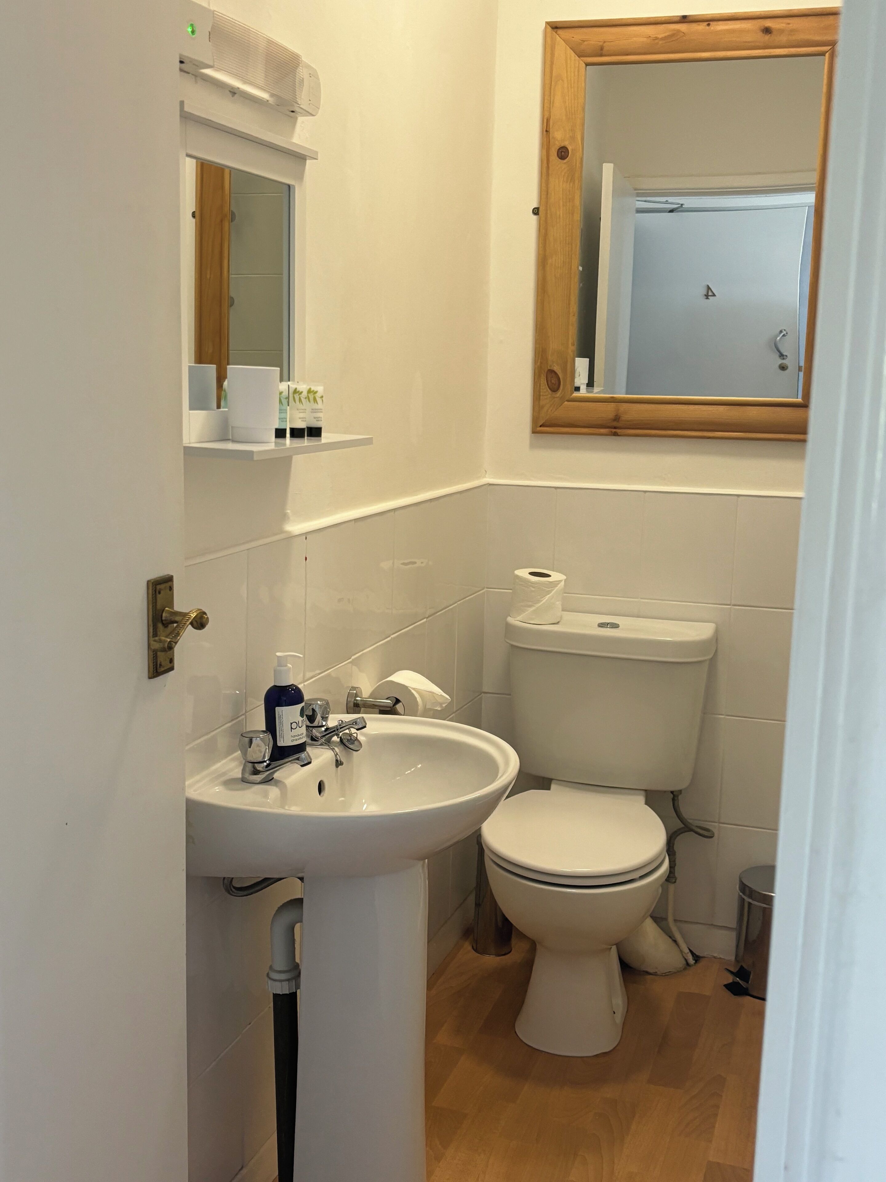 A small, clean bathroom with a white sink, toilet, and mirror.