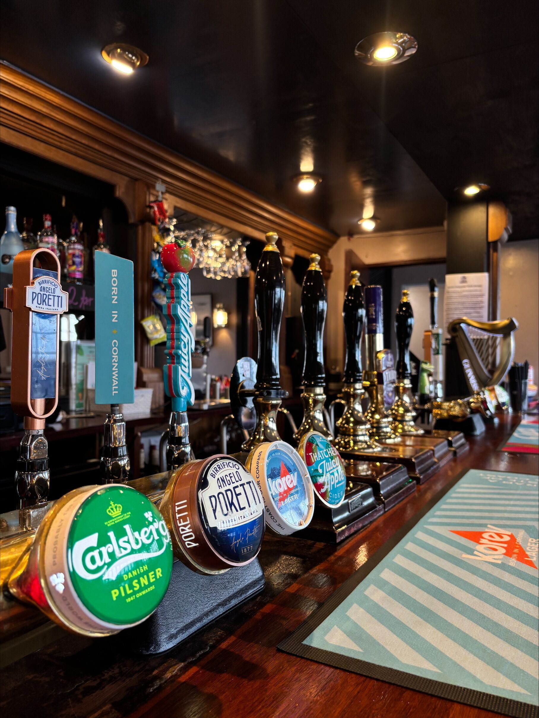A bar with various beer taps and a selection of bottles.