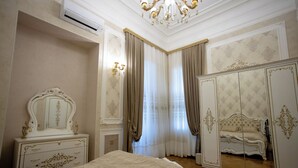 A bedroom with a large bed, a dresser, a mirror, and a wardrobe.