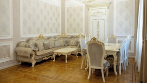A room with a sofa, dining table, chairs, and a chandelier.