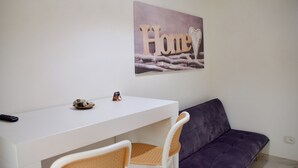Ett rum med ett vitt skrivbord, en lila soffa och en tavla på väggen som föreställer ordet ”Hem” tillsammans med ett hjärta.