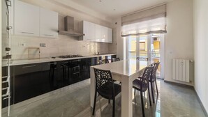 Une cuisine moderne avec des meubles de rangement noirs et blancs, un îlot central doté de chaises et une vue sur l’extérieur.