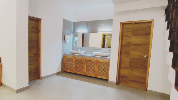 Un baño de hotel con un banco de madera, dos lavamanos y un espejo grande.