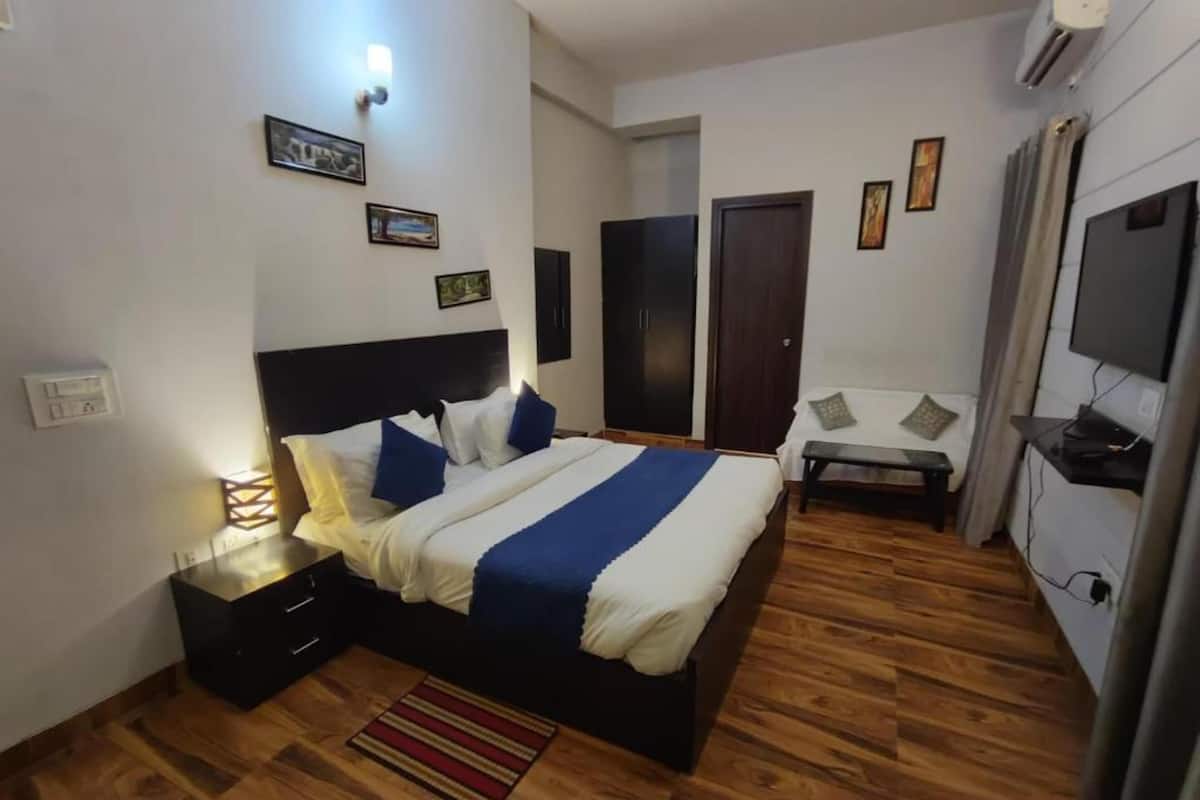 A bedroom with a bed, bedside tables, a desk, a chair, a TV, and a wardrobe.