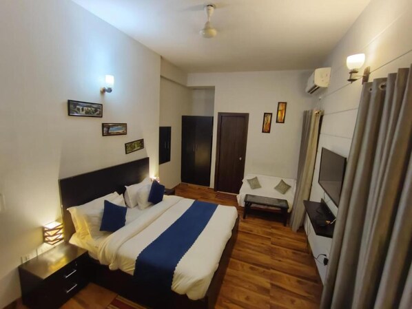 Une chambre à coucher avec un lit, des tables de chevet, une télévision et une armoire.