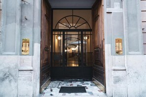 A hotel entrance with a glass door, a tiled entrance area, and a sign indicating the property is a condominium. - Lovely Rooms Vatican (Rome)