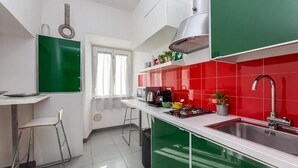 Eine moderne Küche mit grünen und roten Fliesen, einem Edelstahl-Spülbecken und einem Fenster mit Vorhängen.