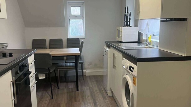 Een moderne keuken met een eethoek, inclusief een magnetron, spoelbak en wasmachine.