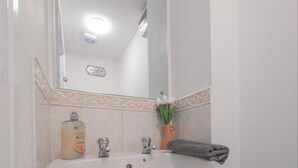 Une salle de bain avec un lavabo blanc, un miroir et une serviette posée sur le comptoir.
