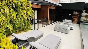 A rooftop terrace with outdoor seating, a green wall, and a view of the cityscape. - Itaim Retreat Luxury 1 Bedroom in Itaim (São Paulo)