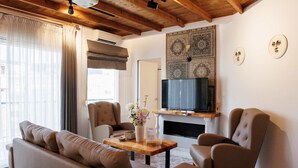 Una sala de estar con un sofá, sillones, una mesa de centro de madera, un televisor de pantalla plana y una chimenea.
