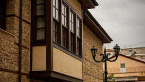 Un edificio de piedra con balcón, una farola y coches aparcados.