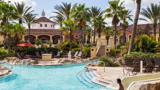 A pool area with a large pool, lounge chairs, and palm trees. - 3602 Fantastic 4BD Townhouse For Family Vacation (Davenport)