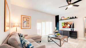 A modern living room with a sofa, coffee table, and a TV mounted on the wall. - 3602 Fantastic 4BD Townhouse For Family Vacation (Davenport)