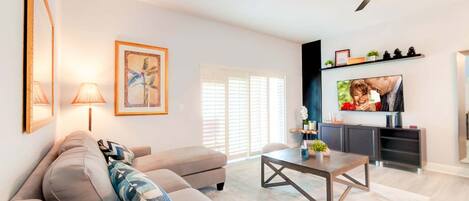 A modern living room with a sofa, coffee table, and a TV mounted on the wall.