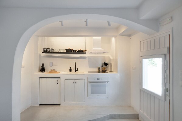 A compact kitchen with white cabinetry, a built-in oven, and a window. - Seafront Pouletis Family Drosoula Gem With Pool (West Mani)
