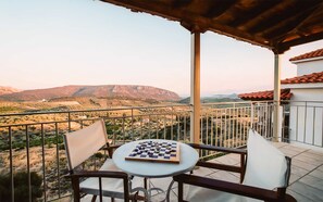 Ein Balkon mit Tisch und Stühlen mit Blick auf eine gebirgige Landschaft.