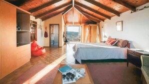 A cozy bedroom with a wooden ceiling, a bed with pillows, a nightstand, and a red bean bag chair. - Villa Oneirama - Nafplio Garden Retreat (Nafplio)